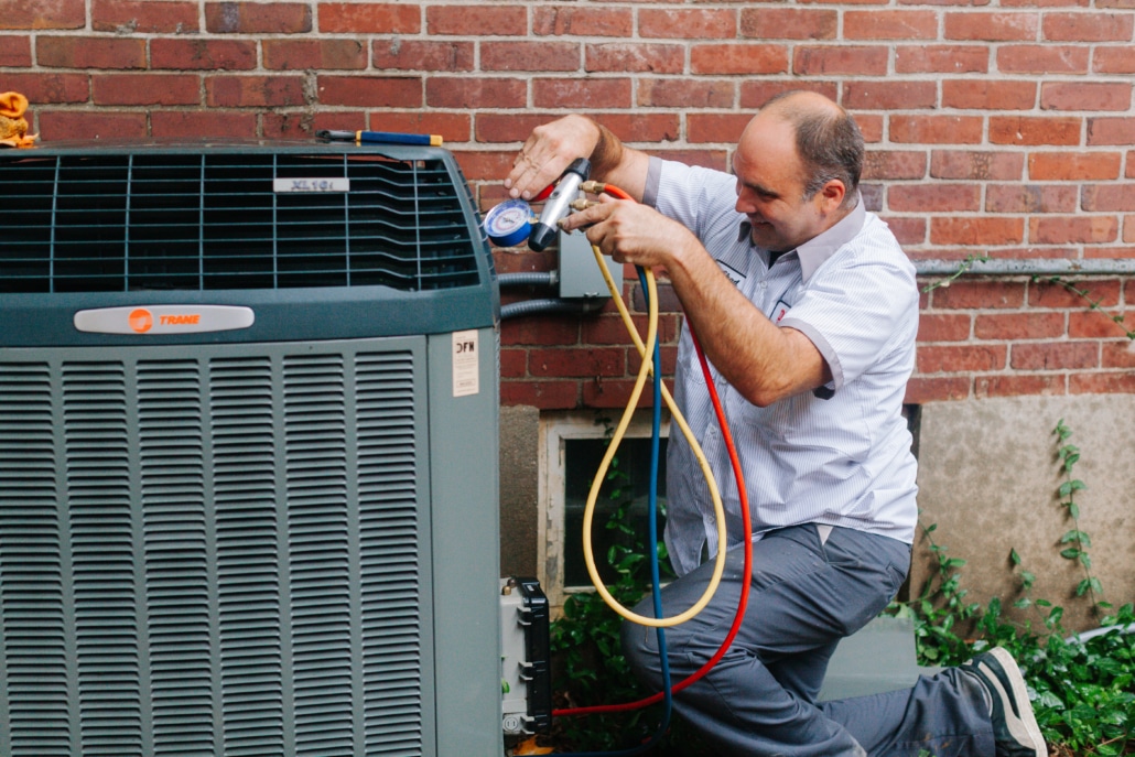 DFH HVAC technician checking refrigerant levels on an outdoor air conditioning unit