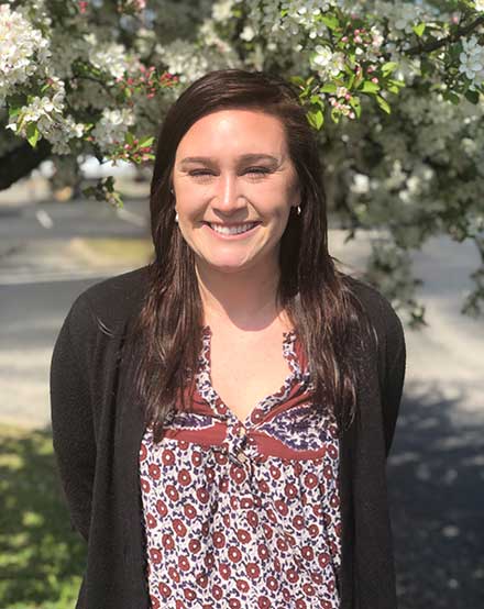 Portrait of woman in a fun top with flowers behind her