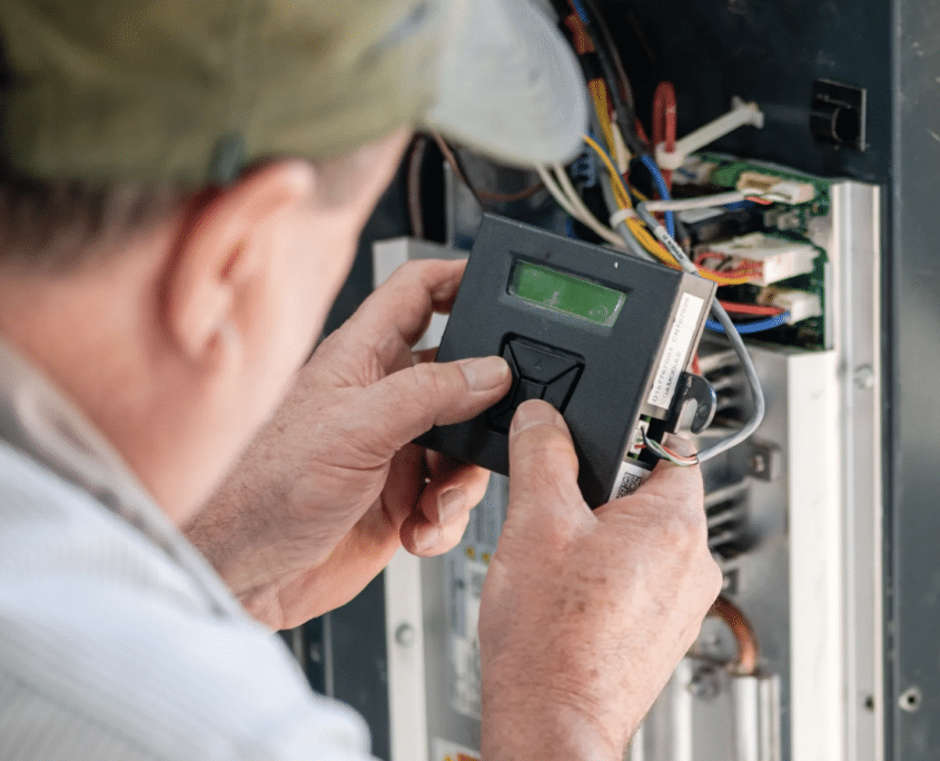 DFH HVAC technician testing electronic controls inside a heating and cooling system