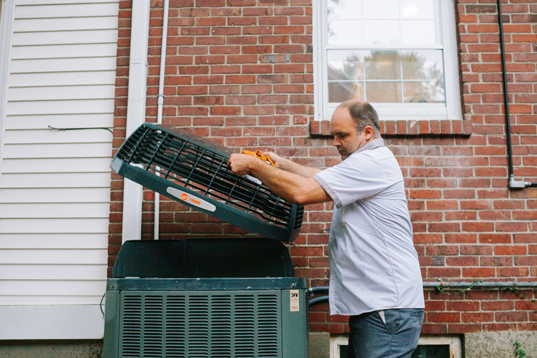 HVAC technician installing or lifting an outdoor air conditioning unit